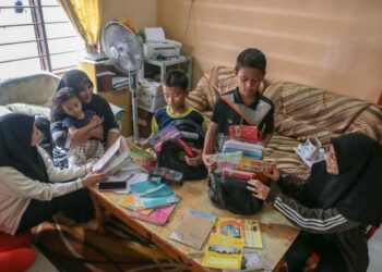 Mazkiah Mohd Salleh, 40 (dua dari kiri) melihat anak-anaknya, (dari kanan) Farah Husna Mohd Zamri, 17, Al Amin Husni Mohd Zamri, 11, Adam Husni Mohd Zamri, 9; dan Maisarah Husna Mohd Zamri, 14, (kiri sekali) yang bersekolah di Sekolah Menengah Kedawang dan Sekolah Kebangsaan Temonyong melakukan persiapan persekolahan di rumah mereka di Kampung Temonyong. – MINGGUAN/SHAHIR NOORDIN