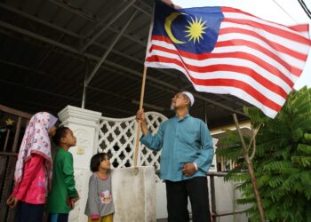 Ahmad Ramli memasang Jalur Gemilang sambil diperhatikan anak-anaknya, Nur Afiqah, 10; Muhammad Haziq, 8; dan Nur Khadijah, 6, di rumah mereka di Zon Kenanga, Ambangan Heights, Amanjaya, Sungai Petani, Kedah semalam. – Utusan/Shahir Noordin