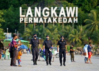 ANGGOTA polis memantau SOP pada hari pertama pembukaan gelembung pelancongan Pulau Langkawi di Pantai Chenang semalam. -UTUSAN/ SHAHIR NOORDIN