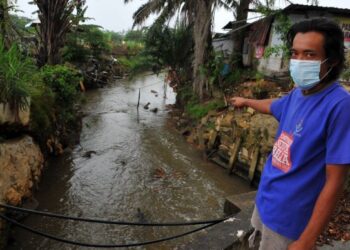 NUR Satria menunjukkan Sungai Kim Kim ketika ditemui di Kampung Bukit Pulai, Pasir Gudang di Johor semalam. – UTUSAN/RAJA JAAFAR ALI