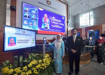 ZALIHA Mustafa (kiri) mengimbas kad perakam waktu sebagai tanda memulakan tugas secara rasmi di Bangunan Kementerian Kesihatan Malaysia, Putrajaya. - UTUSAN/FAISOL MUSTAFA