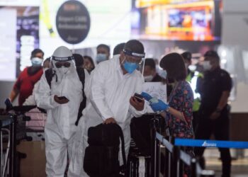 Kelihatan pelancong asing dari warganegara China memakai sut lengkap PPE ketika membuat proses pendaftaran penerbangan di Lapangan Terbang Antarabangsa Kuala Lumpur (KLIA)  pada 2021. - GAMBAR HIASAN