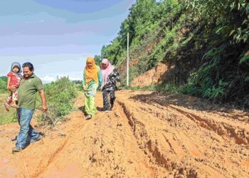 PENDUDUK kampung terpaksa menggunakan jalan yang berlumpur sebagai laluan untuk keluar dari kawasan rumah mereka di Taman Desa Utama, Kampung Kelewek, Tanah Merah, Kelantan. – UTUSAN/KAMARUL BISMI KAMARUZAMAN