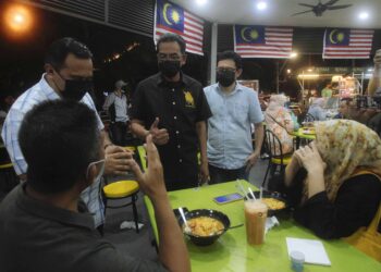 AZMAN Adam (tengah) memeriksa aplikasi MySejahtera pengunjung yang sudah lengkap 2 dos semasa menyertai Operasi Samar A342 di premis makanan sekitar Ayer 8, Presint 8 di sini, hari ini. -UTUSAN/ FAISOL MUSTAFA