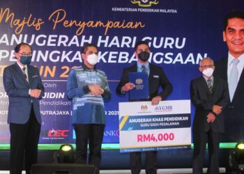 RADZI Jidin menyampaikan Anugerah Gigih Pedalaman kepada Marno Azman Omar (dua kanan) pada Majlis Penyampaian Anugerah Hari Guru Peringkat Kebangsaan Tahun 2021 di Putrajaya. - UTUSAN/FAISOL MUSTAFA