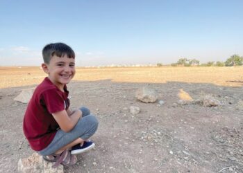 YASSER tersenyum ketika gambarnya dirakam sedang duduk di tepi tanah yang gersang di sebuah perkampungan terpencil Al-Bab, Syria. Syria memerlukan proses kedamaian segera bagi menjamin masa depan anak-anak kecil yang kebanyakannya tercicir daripada sistem pendidikan. – UTUSAN/METRA SYAHRIL MOHAMED