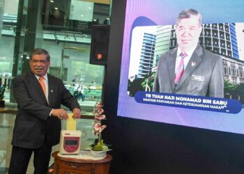 MOHAMAD Sabu mengetip kad perakam waktu pada hari pertama beliau memulakan tugas secara rasmi di Kementerian Pertanian dan Keterjaminan Makanan, Putrajaya. - UTUSAN/FAISOL MUSTAFA