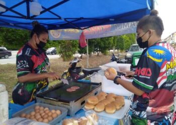 NOORSHAZRINIE Iyali (kiri) dibantu rakannya, Norfazlinda Ismail menyediakan burger untuk dijual kepada pelanggan di Taman Paya Emas, Cheng, Melaka. – minggguan/MUHAMMAD SHAHIZAM TAZALI