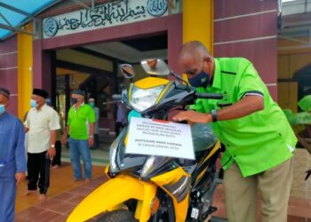 SETIAUSAHA Kerja Masjid Nur As-Sa’aadah, Kampung Pengkalan Batu, Melaka, Mahmood Hassan memasang kad keterangan peraduan pada motosikal Modenas Kriss 110 di bawah Program Istiqamah Subuh dan Isyak Berjemaah 40 Hari.