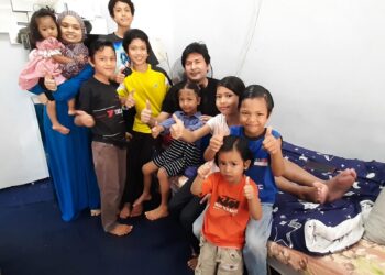 MOHD. AZIZAN Baba, isteri serta lapan orang anak mereka menunjukkan isyarat bagus sebagai tanda ucapan terima kasih kepada Tunku Ismail yang memberi sumbangan RM50,000 kepada beliau dan keluarganya. - UTUSAN/