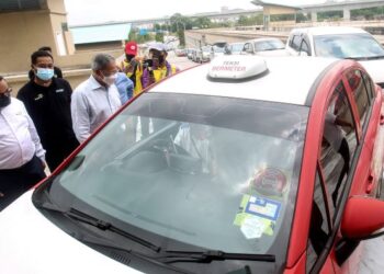 MUSTAPA Mohamed (tiga kiri) beramah mesra dengan pemandu e-hailing selepas menyerahkan sumbangan bakul makanan secara pandu lalu pada Majlis Program Pemberian Bakul Makanan kepada Pekerja Gig Ekonomi dan Bekas Petugas Media di Putrajaya Sentral. - UTUSAN/FAISOL MUSTAFA