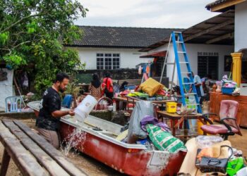 MOHD. ARIFF Bidin (kiri) dan keluarga membersihkan rumah mereka selepas banjir kilat di Kampung Blok C Ampangan, Seremban surut, semalam. – UTUSAN/MUHAMMAD IZZAT TERMIZIE.