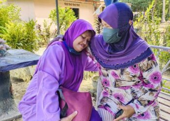 MAZIYA Abdul Magaid (kanan) ceria melayan anak sulungnya, Nazarina Wahab yang merupakan seorang OKU ketika ditemui di kediamannya di Kampung Seberang Batu Hampar, Rembau hari ini.-UTUSAN/NOR AINNA HAMZAH