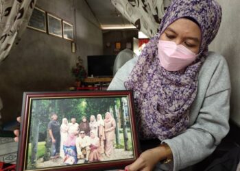 NOORSAFURAH  Mohd. Yassin menunjukkan gambar mereka lapan beradik dan kedua-dua arwah ibu dan bapa mereka ketika sambutan Aidilfitri pada tahun 2018 ketika ditemui Mingguan Malaysia di Rumah Rakyat Repah, Tampin, semalam. – UTUSAN/NOR AINNA HAMZAH