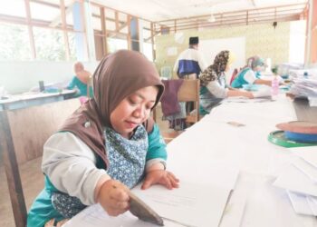 HAFIMAZATUL Ashikin yang mempunyai kekurangan fizikal sedang menghasilkan sampul surat di Bengkel Seri Sembilan, Mambau, Seremban.-UTUSAN/NOR SHAFAWATI YUP