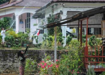 PENDUDUK di Felda Raja Alias 1, Jempol, Rogayah Ahmad, 68, dan jirannya, Adenan Rauf, 63, menyiram ke atas bumbung rumah masing-masing sebagai kaedah mengurangkan bahang ekoran cuaca panas yang melanda ketika ini. – UTUSAN/MOHD. SHAHJEHAN MAAMIN