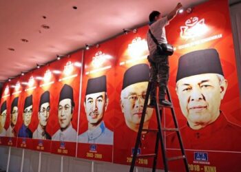 SEORANG juruelektrik memasang lampu pada gambar-gambar Presiden UMNO sebagai persiapan menjelang Perhimpunan Agung UMNO (PAU) 2021 di Dewan Merdeka, Pusat Dagangan Dunia Kuala Lumpur. - UTUSAN/MUHAMAD IQBAL ROSLI