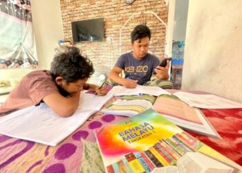 DANIEL HAKIM MOHD. ZAKI (kanan) bersama adiknya, Daniel Haziq Mohd Zaki mengikuti proses PdPR di rumah mereka di Kampung Sungai Padang, Simpang Empat, Perlis hari ini.- UTUSAN/NAZLINA NADZARI