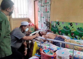 MOHD. Akmal Kamarudin (tengah) berbual dengan Wan Ali  Mustaffa yang terlantar akibat angin ahmar manakala dua lagi kakaknya juga terlantar akibat masalah kesihatan di Selama dekat Larut semalam. -UTUSAN/WAT KAMAL ABAS