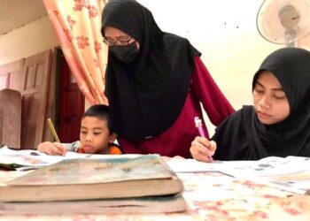 NOR Azizah Nordin (tengah) memantau anak-anaknya, Muhammad Zhafran Hakim (kiri) dan Nur Zatul Athirah ketika sesi PdPR di kediaman mereka di Perumahan Awam II, Malim Nawar. – UTUSAN/LIYANA RAMLI