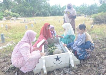 TUJUH beradik yatim piatu menziarahi kubur bapa mereka di Tanah Perkuburan Islam Parit 1C Sungai Manik dekat Teluk Intan, Perak, semalam. - FOTO/AIN SAFRE BIDIN