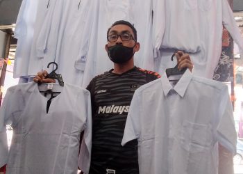 PEMBORONG yang juga pengedar pakaian sekolah, Ahmad Saufiq Mohamad, 38,  menunjukan baju sekolah yang dijual di kedainya ketika tinjauan di Bagan Serai hari ini. - UTUSAN/ WAT KAMAL ABAS