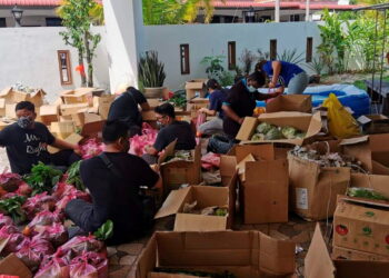 SUKARELAWAN membungkus sayur yang tiba dari Cameron Highlands untuk diagihkan kepada penduduk di sekitar Lumut baru-baru ini.