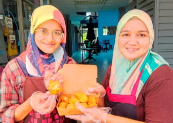 Nor Farhana Fatihah Abu Bakar (kiri) dan kakaknya Nor Faizatul Shawani menunjukkan durian goreng RM1 seulas yang mereka dijual di Sungai Siput. - UTUSAN/MOHAMAD HAFIZI MOHD. SAID
