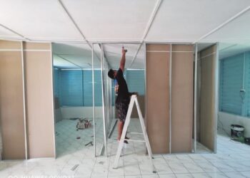SEORANG kontraktor warga asing membina rumah penduduk di Kampung Bahagia, Teluk Intan semalam. - UTUSAN/AIN SAFRE BIDIN