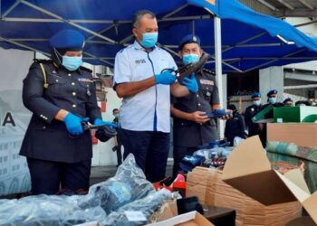 SAIFULLIZAN Kamarul Zaman (tengah) menggunting kasut tiruan dalam operasi melupuskan barang rampasan di Stor Eksibit KPDNHEP Perak di Ipoh hari ini. - UTUSAN