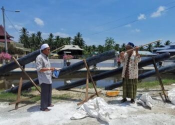 SHAKAWI Salleh (kanan) bersama  rakannya menunjukkan cara membakar meriam di depan masjid Kampung Sungai Nipah Darat  Rungkup di Bagan Datuk.  -UTUSAN/AIN SAFRE BIDIN