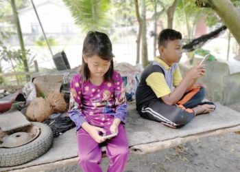 Nurallisyazana Abdullah (kiri) dan Nazirul Badrul mengikuti pengajaran dan pembelajaran di rumah (PdPR) menggunakan telefon bimbit di Kampung Redang Punggor, Chenderong Balai, semalam. -UTUSAN/AIN SAFRE BIDIN