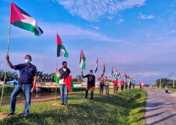 AZHAR Hashim (kiri) bersama golongan anak muda memegang Palestin sebagai tanda solidariti ketika memasang bendera negara berkenaan di Kampung Parit Haji Taib 3, Bagan Serai. - UTUSAN/WAT KAMAL ABAS