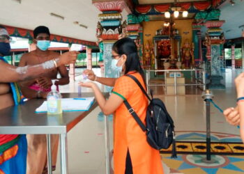 SAMI, B. Rajamani memeriksa suhu pengunjung untuk bersembahyang sempena Deepavali di Kuil Seri Maha Mariaman di Teluk Intan hari ini. - GAMBAR AIN SAFRE BIDIN