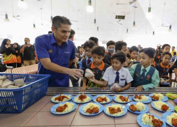 RADZI Jidin membantu memberikan juadah kepada murid-murid ketika mengadakan lawatan ke Sekolah Kebangsaan Putrajaya Presint 9(2), Putrajaya di sini, hari ini.-UTUSAN/ FAISOL MUSTAFA