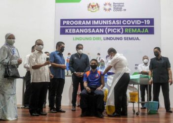 Timbalan Menteri Kesihatan 1, Datuk Dr. Noor Azmi Ghazali (dua kanan) memberi suntikan vaksin kepada pelajar, Haziq Zafri Hiruddin, 17, sambil diperhatikan Menteri Kesihatan, Khairy Jamaluddin (empat kiri) dan Menteri Kanan Pendidikan, Datuk Seri Dr. Radzi Jidin (tiga kiri) pada Program Imunisasi COVID-19 Kebangsaan (PICK) Remaja di SMK Presint 8 (1) Putrajaya di sini, hari ini. - UTUSAN/FAISOL MUSTAFA