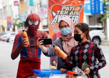 Muhammad Zakri Mohamed Sofi bergambar swafoto bersama pembeli  di Jalan Puncak Jalil, Seri Kembangan, baru-baru ini. – UTUSAN/FAISOL MUSTAFA