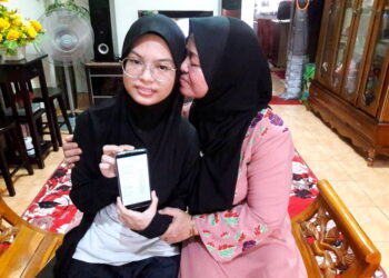 PADILAH Mohamed (kanan) mencium Nur Alia Maisarah Razmin selepas melihat keputusan SPM anaknya yang cemerlang di rumah mereka di Taman Pasak Indah di Kota Tinggi, Johor.  semalam -UTUSAN/MASTURAH SURADI