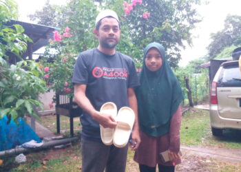 KHAIRUDIN Mohd. Daud dan anaknya, Nur Safia Humaira menunjukkan selipar putih milik Muhammad Yusuf. Kanak-kanak itu ditemukan mati lemas ketika berkelah bersama ahli keluarga di Sungai Ketil berhampiran Loji Air Sungai Limau di Kupang, Baling.