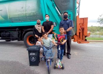 ZAYN Asyraff (depan, kiri) di sisi tong sampah kecil kegemarannya bersama ibu bapanya Norfaizah Mohd. Esa (belakang, kiri) dan Mohamad Aliff Hakim Jais (tengah) dan Mohd. Asriff Samion (kanan) merakam gambar di hadapan lori kompaktor SWM Environment yang singgah ke rumah keluarga itu di Taman YPJ, Kota Tinggi di Johor. -UTUSAN/MASTURAH SURADI