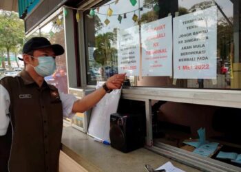 MOHD. Ridzuan Mohd. menunjukkan papan tanda memaklumkan perkhidmatan teksi rentas sempadan JB-Singapura kembali beroperasi bermula hari ini di Larkin Sentral, Johor Bahru. -UTUSAN/KHAIRUL MOHD ALI
