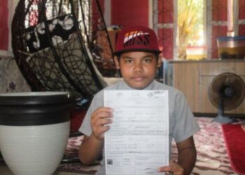 MUHAMMAD Faiz Naqqiudin Abdullah menunjukkan sijil kelahiran ketika ditemui di rumah ibu angkatnya di Kampung Ayer Baloi, Pontian, Johor. – UTUSAN/MUHAMMAD ZIKRI