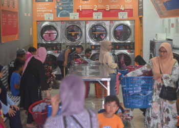 Orang ramai memenuhi kedai dobi layan diri di Marang, Terengganu sewaktu musim tengkujuh.  - GAMBAR HIASAN
