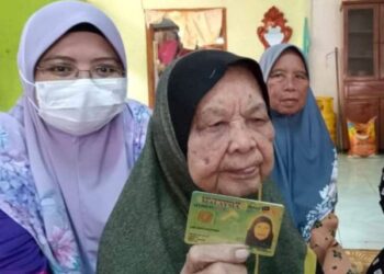 UMI Kastawi menunjukkan kad pengenalannya sambil ditemani Nurhayati Khalil ketika ditemui di Lenga, Muar di Johor. -UTUSAN/FARAHWAHIDA AHMAD
