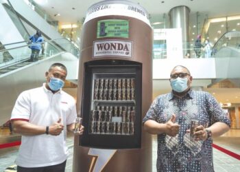 MOHD. Hapiz Mohd. Salleh dan Mohd. Faiz Anuar mendapatkan Kopi Wonda yang diedar secara percuma melalui peti ais tanpa sentuhan di Bangsar, Kuala Lumpur, semalam. – utusan/MOHD FARIZWAN HASBULLAH