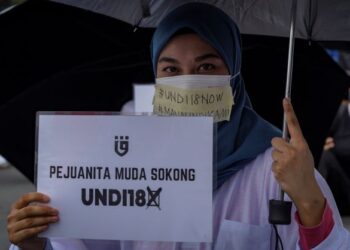 Seorang ahli parti Pejuang memegang plakad menyokong usul ‘Undi 18’ pada Himpunan Tuntut Undi 18 di hadapan Bangunan Parlimen Malaysia, Mac lalu. - UTUSAN/MUHAMAD IQBAL ROSLI