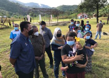 ABDUL Rahman Mohamad (kiri) menyantuni Orang Asli yang menerima suntikan vaksin di Pos Gob, Gua Musang, Kelantan hari ini. - UTUSAN/AIMUNI TUAN LAH