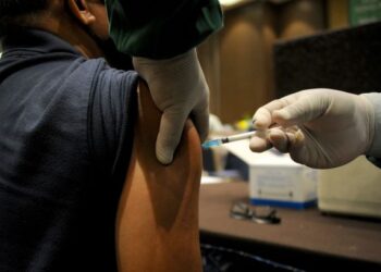 SEORANG penduduk menerima suntikan vaksin Covid-19 di sebuah pusat vaksinasi di Indonesia. - AFP