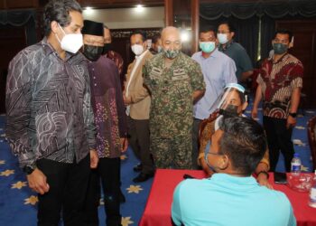 KHAIRY Jamaluddin beramah mesra dengan penerima vaksin yang menunggu giliran di Kompleks Kota Darulnaim, Kota Bharu, Kelantan, hari ini. - UTUSAN/ZULHANIFA SIDEK