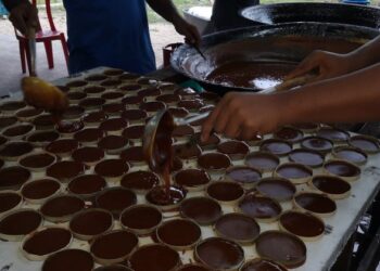 Kerja menuang cecair likat manisan ke dalam acuan daun mengkuang.